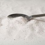 Colágeno em pó espalhado com uma colher metálica.