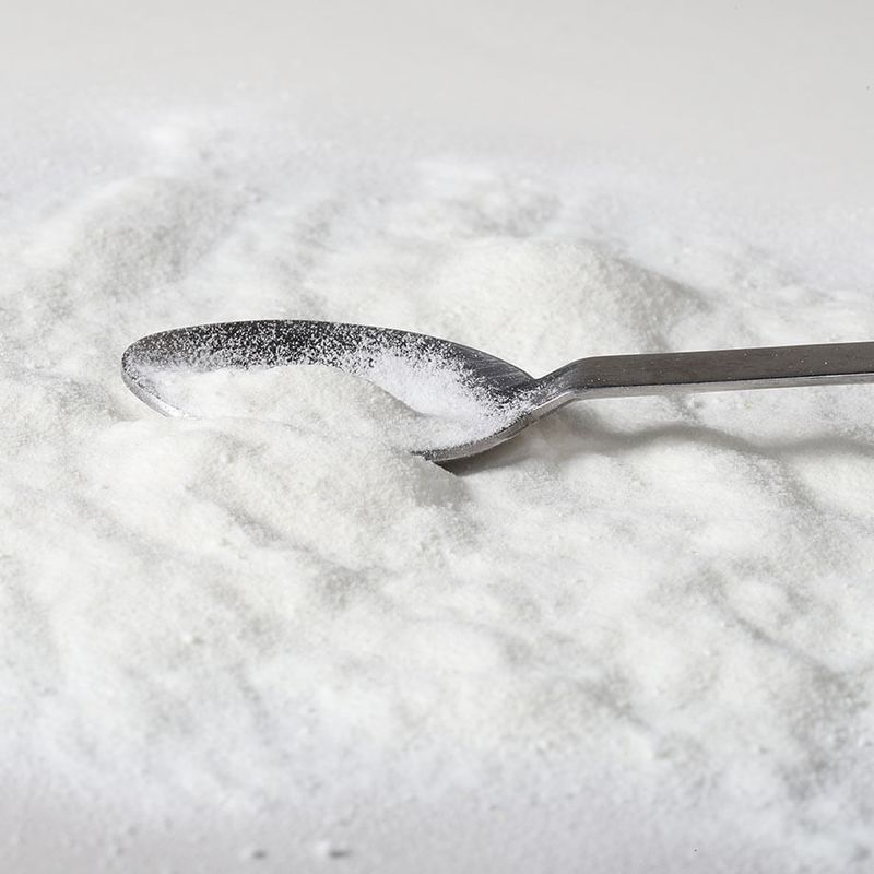 Colágeno em pó espalhado com uma colher metálica.