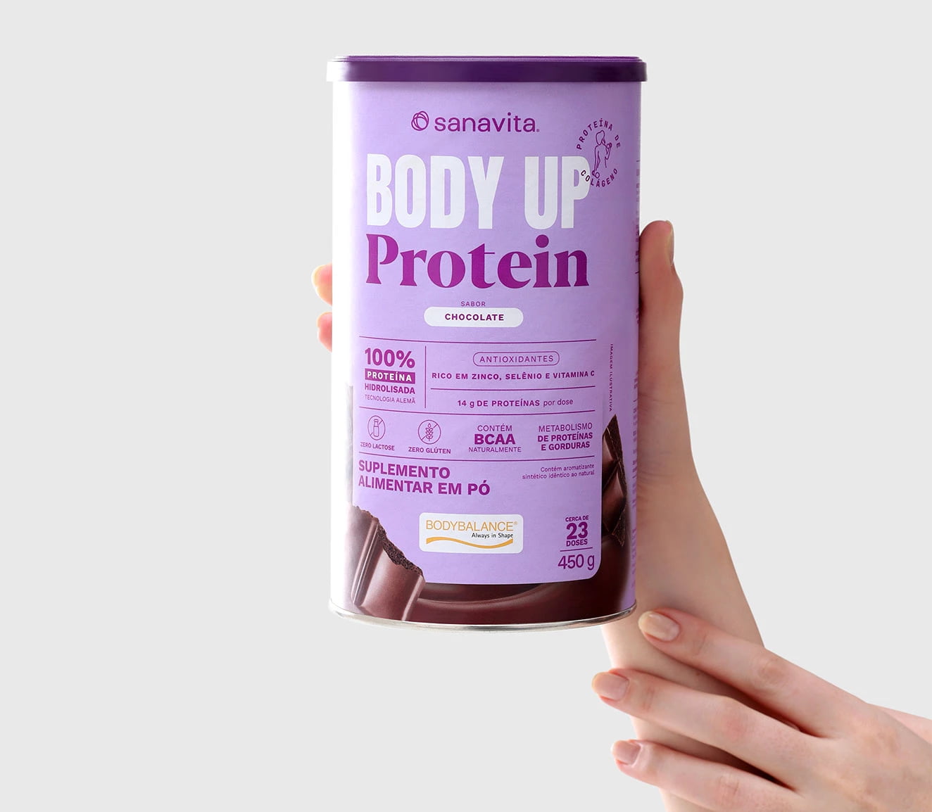Pessoa segurando o pote de Body Up Protein da Sanavita, sabor chocolate, com informações sobre a proteína e o conteúdo nutricional visíveis na embalagem.