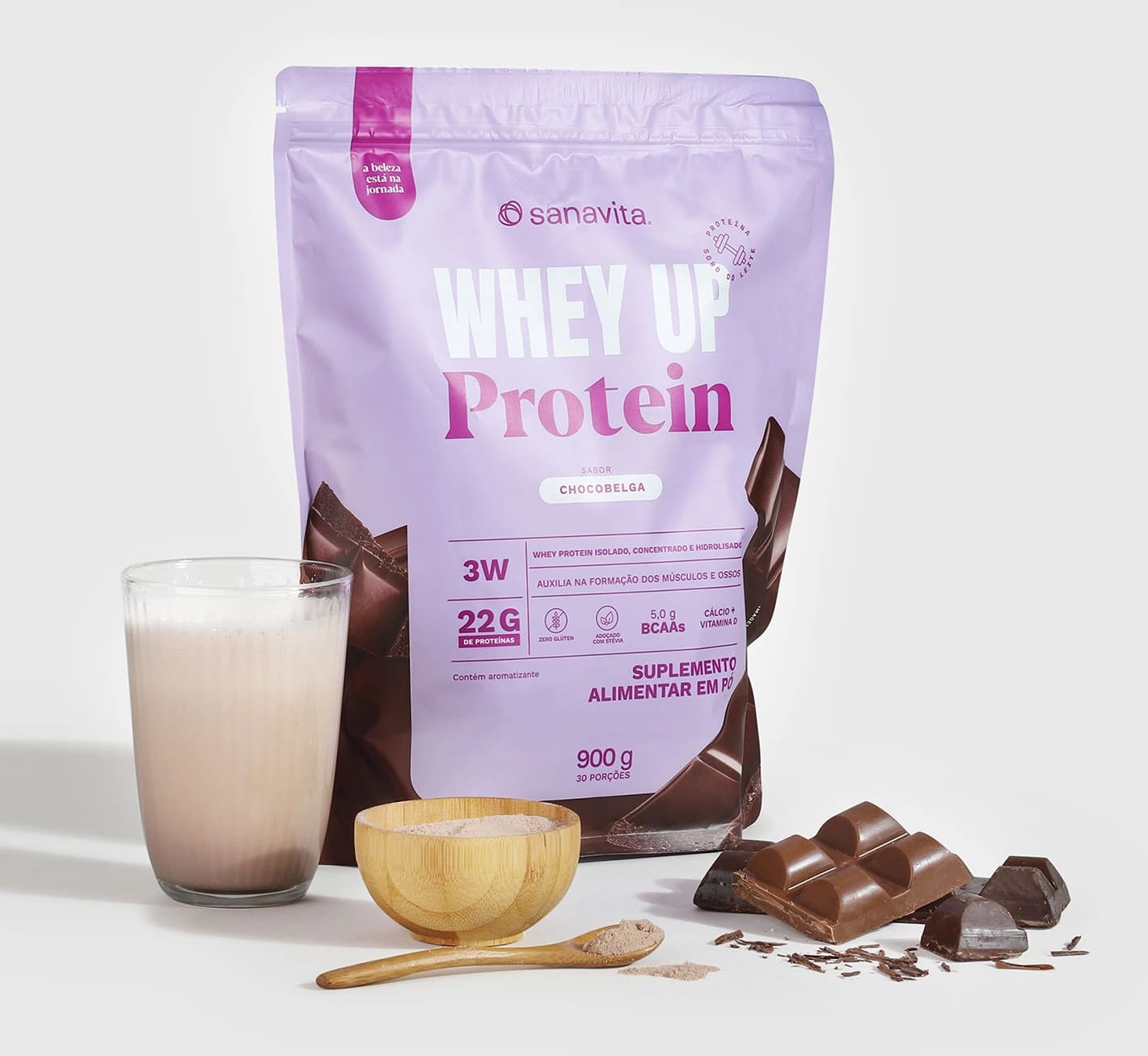 Pacote de Whey Up Protein sabor Chocobelga da Sanavita, ao lado de um copo com bebida cremosa e uma tigela de madeira com pó de proteína.